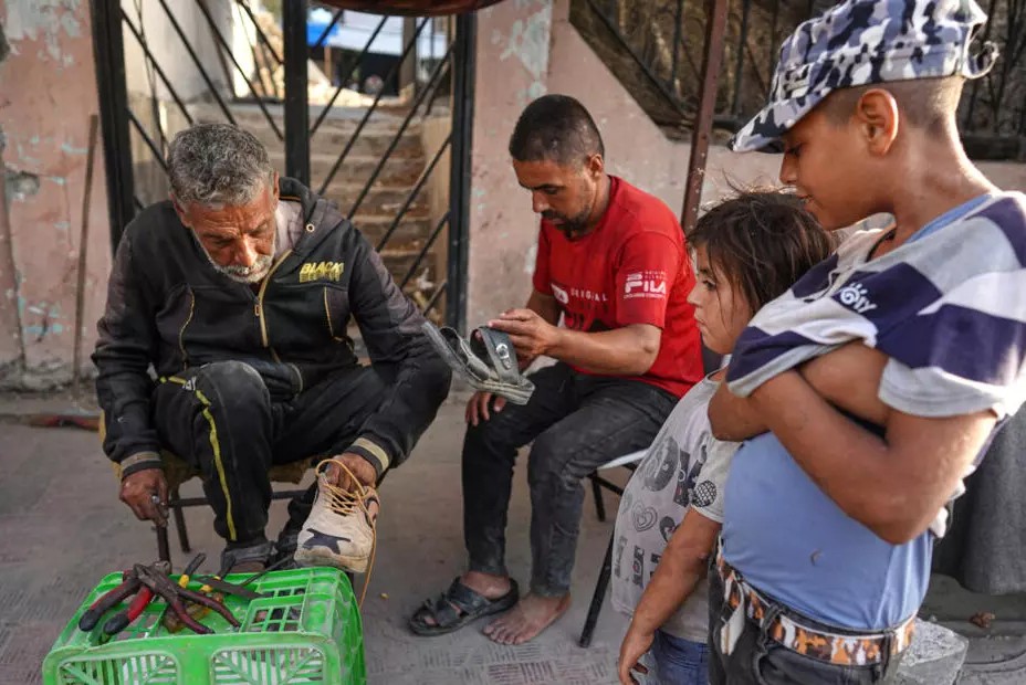 Warga Palestina menunggu tukang sepatu memperbaiki sepatu mereka di Khan Yunis
